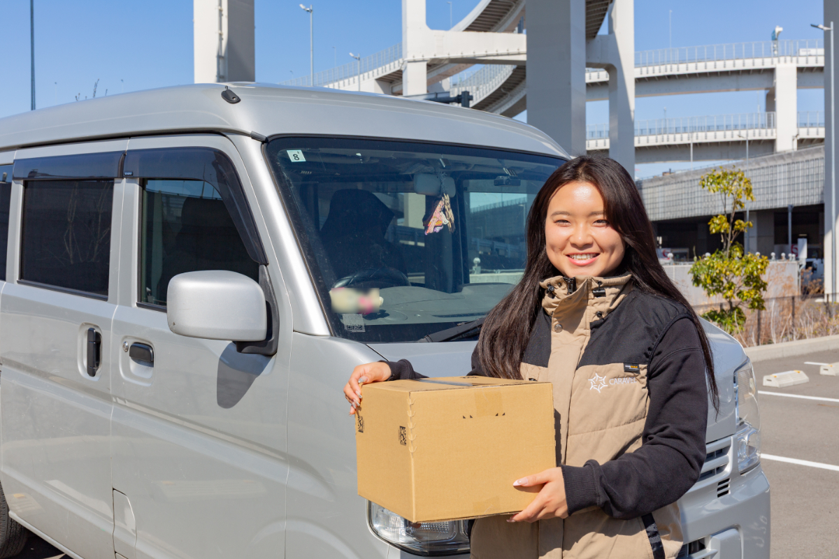 車の前で荷物を持つ村田さん